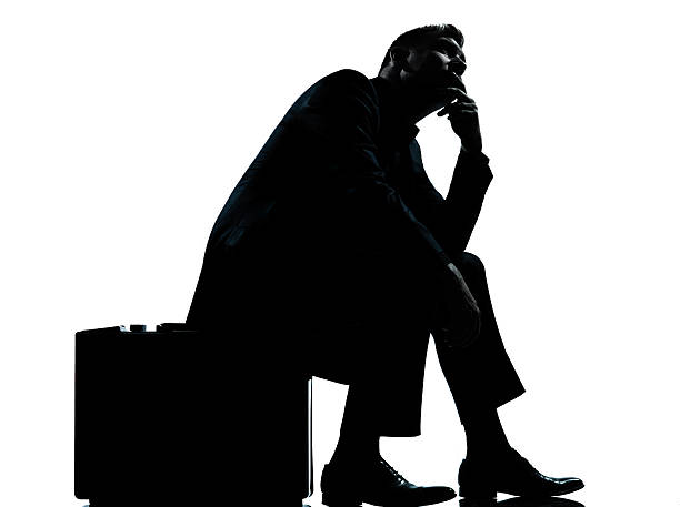 istock one business man sitting on suitcase waiting silhouette 470635417