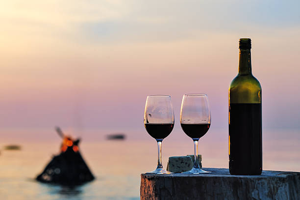 istock Bottle of red wine and two glasses with cheese on tree stump 470636122