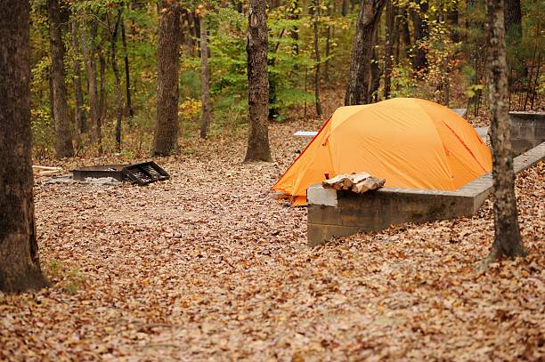 Orange dome tent in campsite with fire pit
