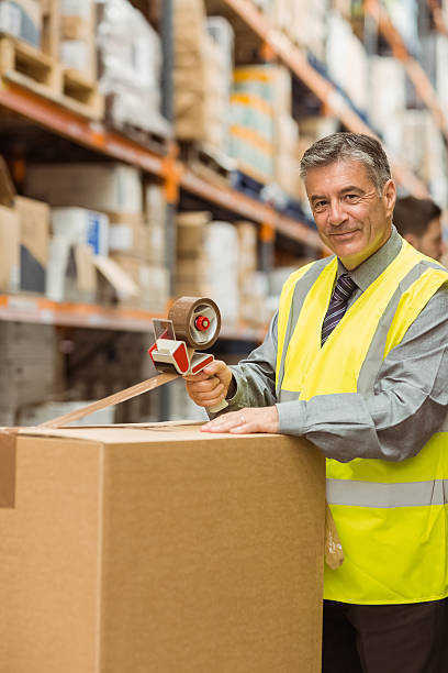 istock Warehouse worker sealing cardboard boxes for shipping 470639616