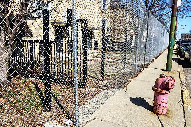 Fenced off and boarded up Frances Cabrini Rowhouses in the Carbrini Green housing project, Near North Side of Chicago. Old fire hydrant on street.  No people.