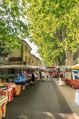 Lourmarin, France - June 13, 2014: People strolling among the market stalls of Lourmarin, where every Friday morning a beautiful Provencal market is held.