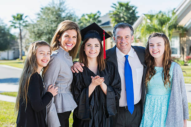 high school graduate posando con su familia - poses para fotos de graduación fotografías e imágenes de stock