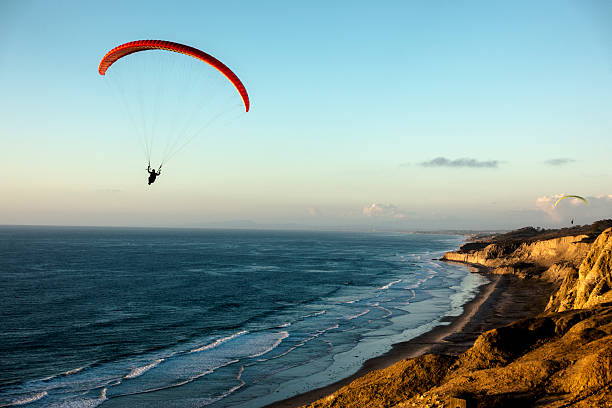Paraglider flying over ocean cliffs at sunset stock photo