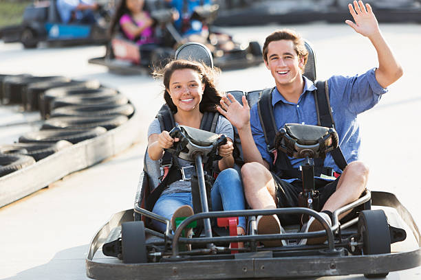 istock Teens riding go carts at amusement park. 470642944