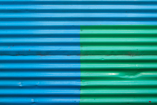 Colorful and full frame background image of a corrugated wall in La Boca district, Buenos Aires. The wall is painted in blue, and green.