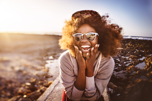 Fun-loving African American hipster teen laughing ahppily while spending a day at the beach