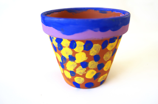 Clay flower pot painted with blue and yellow polka dots