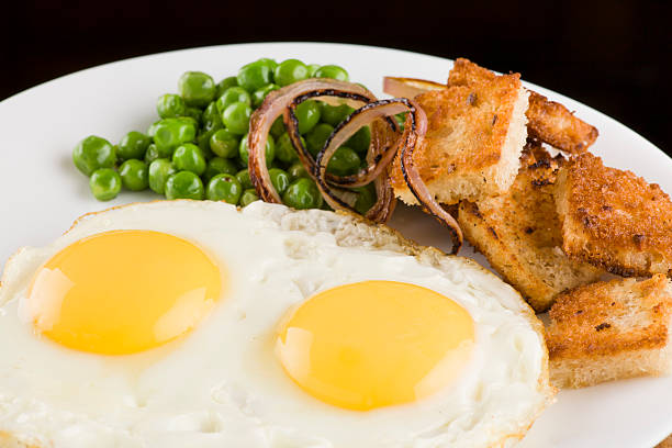 Fried eggs breakfast with peas onion and bread stock photo