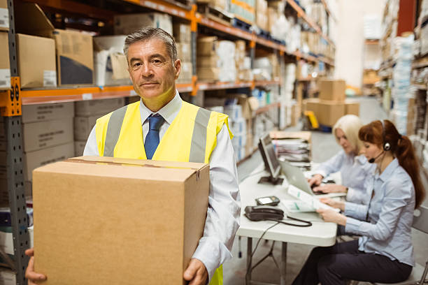 istock Warehouse manager smiling at camera carrying a box 470650646