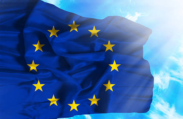 istock European Union waving flag against blue sky with sunrays 470650963