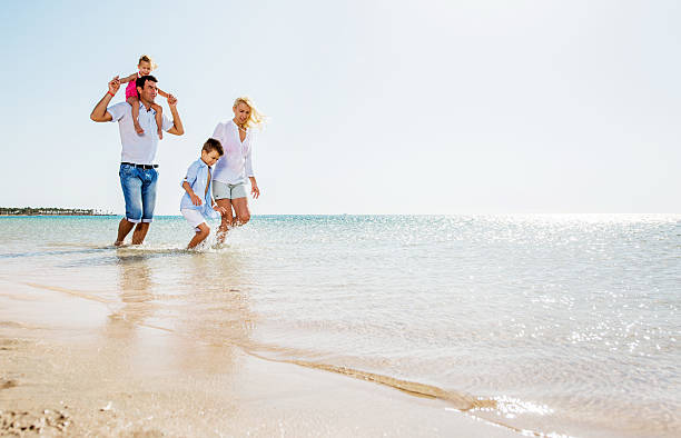 istock Playful family running through sea during summer day. Copy space. 470651566