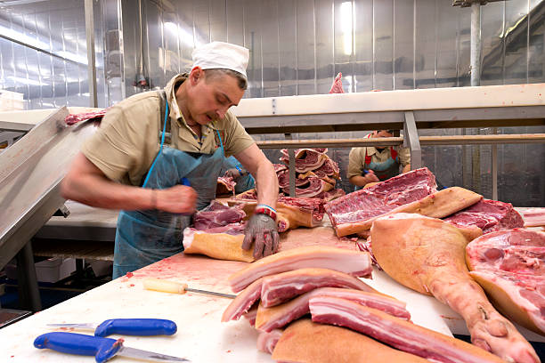 butcher carne de corte en la planta de procesamiento de comida - butcher butchers shop slaughterhouse hook fotografías e imágenes de stock