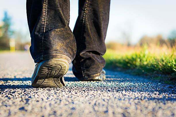 istock Man with dirty boots and jeans walking on a paved road 470657142