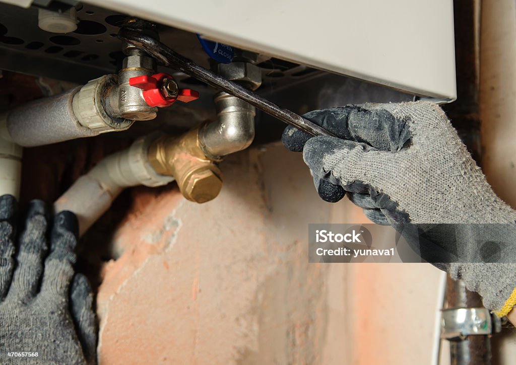 Two gloved hands using wrench to connect a gas boiler Man connects the gas boiler to the pipes with a wrench Natural Gas Stock Photo