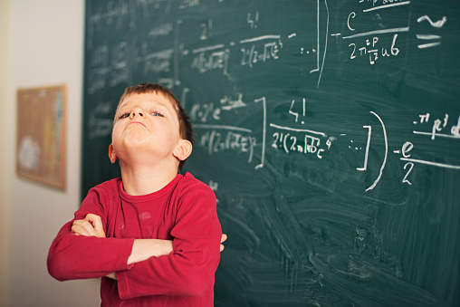 Proud little boy next to blackboard with mathematic equations. Obviously the boy is very proud of his equations.