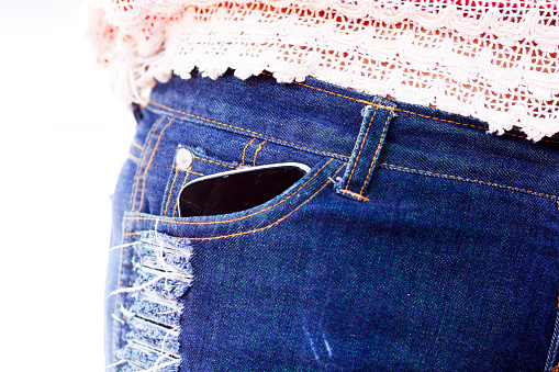 Very used mobile in pocket of blue jeans hot pants of thai girl.