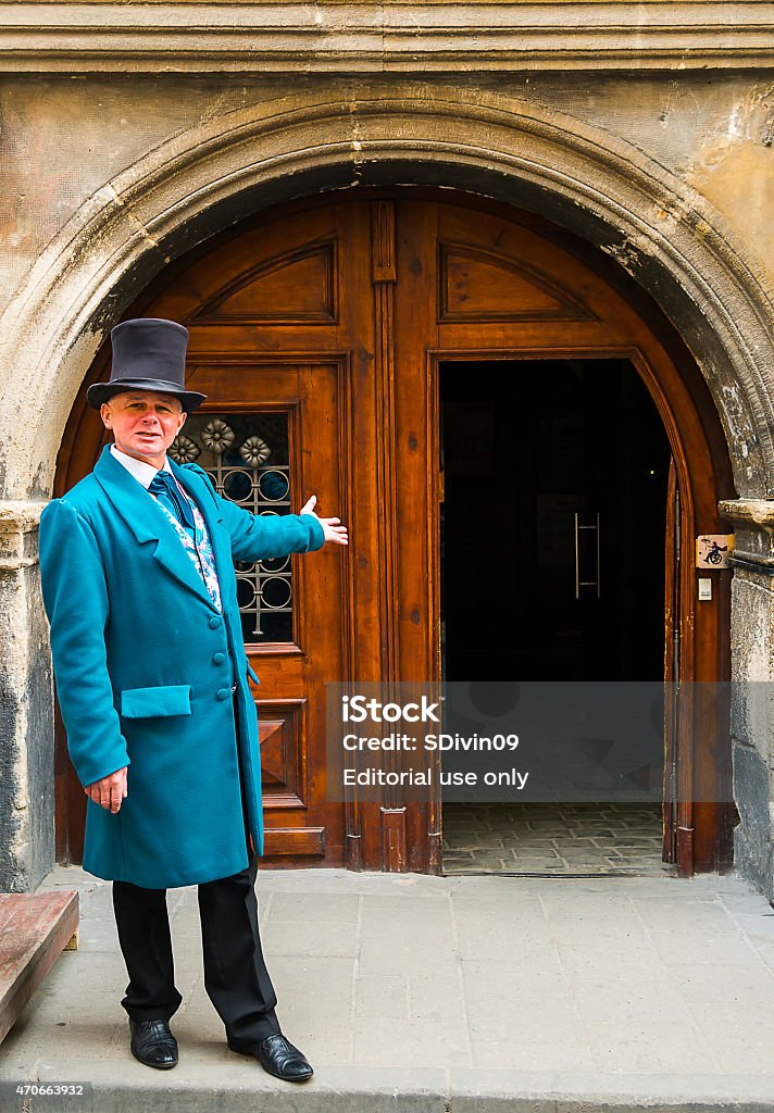 Servant invites enter the old house Lviv, Ukraine - April 14, 2015: An actor in makeup doorkeeper posing in the old town near the town hall Lviv, Ukraine Men Stock Photo