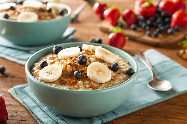 Homemade steel cut bowl of oatmeal in blue bowl Homemade Healthy Steel Cut Oatmeal with Fruit and Cinnamon porridge stock pictures, royalty-free photos & images