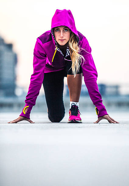 Young woman doing sprints in an urban area, some motion blur, cross-processed image. Horizontal shot.