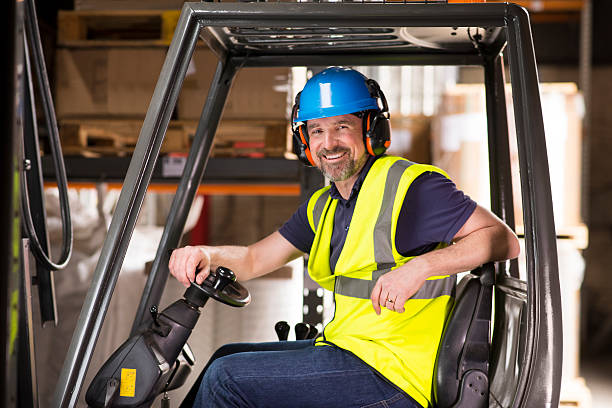happy mature forklift truck driver smiling to camera - chauffeur beroep stockfoto's en -beelden