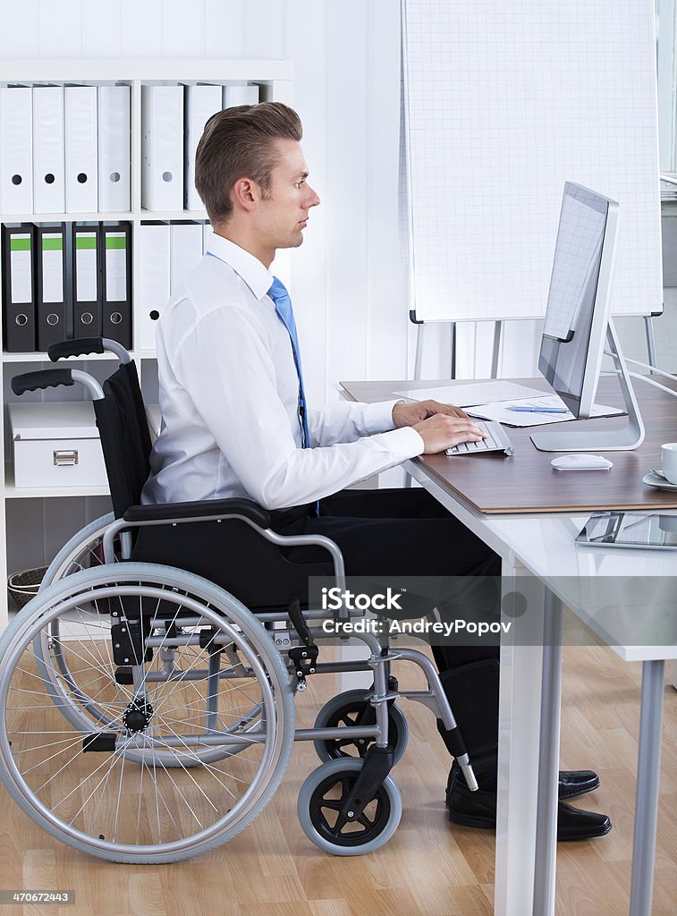 Homme d'affaires, assis sur fauteuil roulant et utiliser l'ordinateur - Photo de Bureau - Lieu de travail libre de droits
