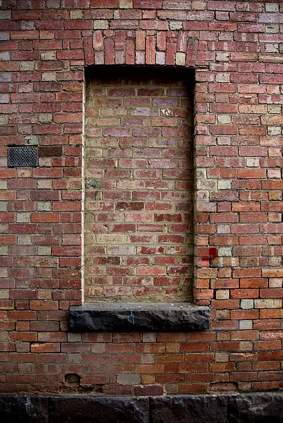  The window of this rustic red brick building that once provided a view is now blocked with red bricks. 