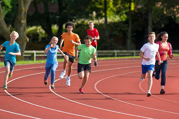 Track Stars Panning shot of a group of teenagers running a track race. track and field stock pictures, royalty-free photos & images