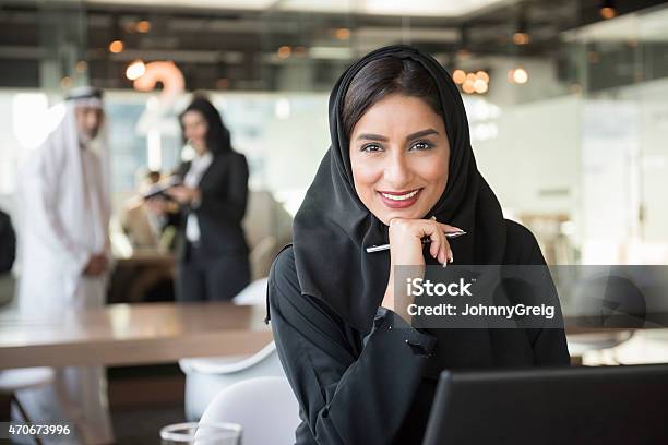 Photo libre de droit de Souriant Arab Femme Daffaires Tenant Le Stylo Dans Le Bureau banque d'images et plus d'images libres de droit de Émirats Arabes Unis