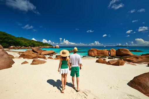 Couple in green walking on a tropical beach at Seychelles