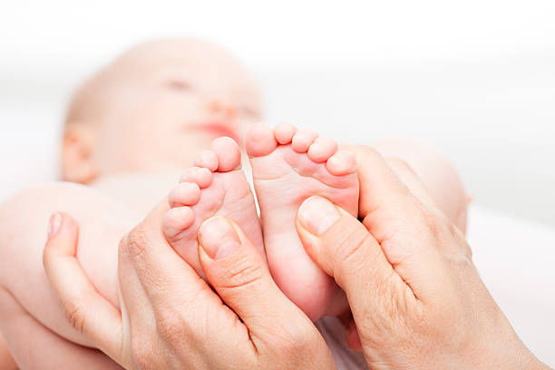 มุ่งเน้นไปที่มือผู้ใหญ่ให้ทารกนวดเท้า - นวดเท้า การนวด ภาพสต็อก ภาพถ่ายและรูปภาพปลอดค่าลิขสิทธิ์