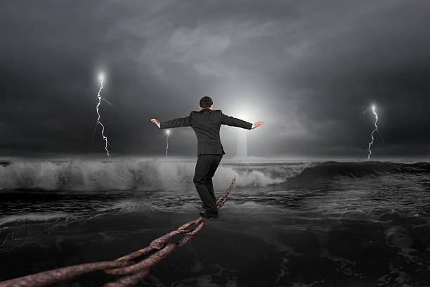 istock Businessman balancing on old iron chain with dark stormy ocean 470681838