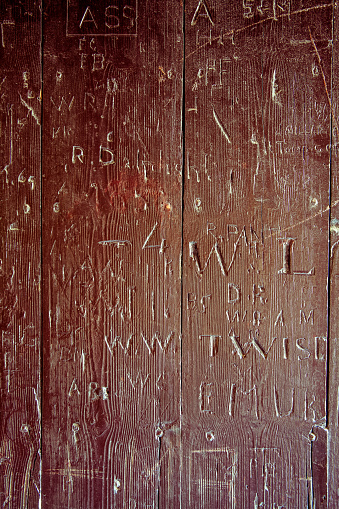 Names and words carved into an old wooden door.