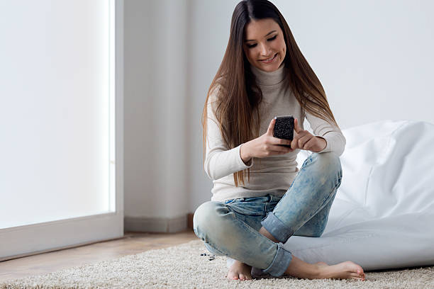 istock Beautiful young woman using her mobile phone at home. 470689610