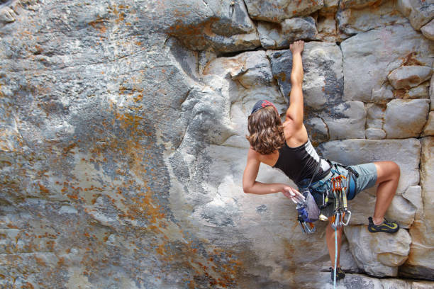 Determined to reach the top Rear view of a female rock climber scaling a rock face rock climbing stock pictures, royalty-free photos & images