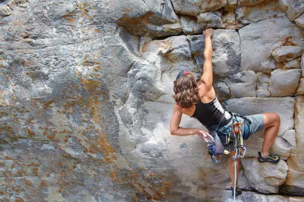 Rear view of a female rock climber scaling a rock face