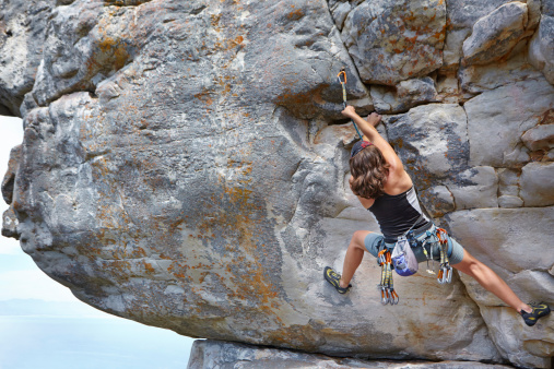 An experienced female rock climber scaling a rock face