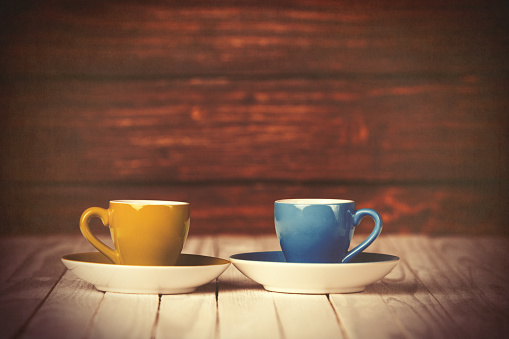 Two cups of coffee on wooden table and background.