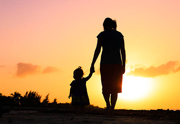 istock mother and little daughter walking at sunset 470714946