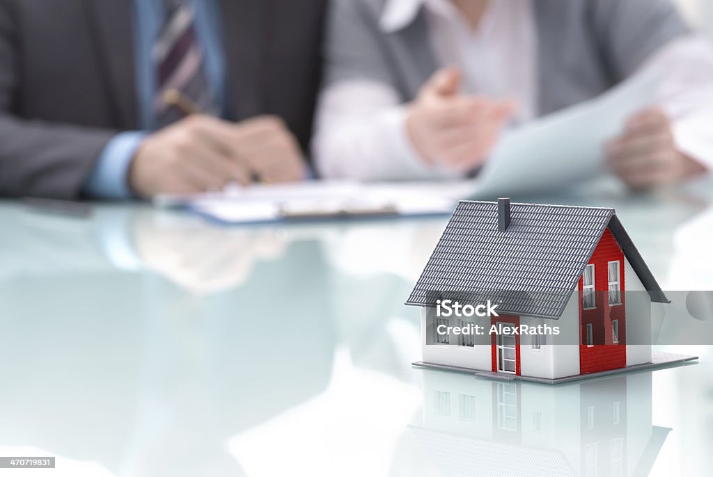 Real estate concept Businessman signs contract behind home architectural model  Mortgage Loan Stock Photo