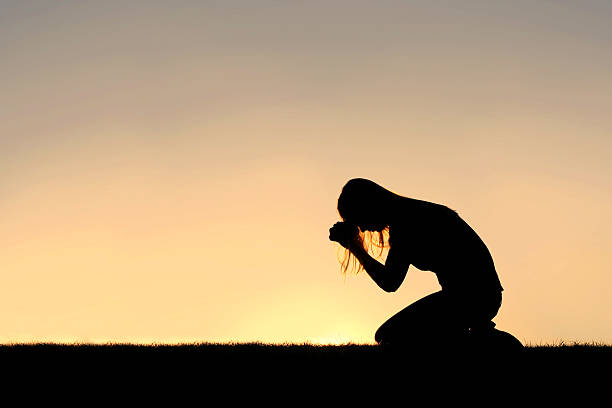 christian frau sitzt in der gebet-silhouette - kneeling praying women begging stock-fotos und bilder