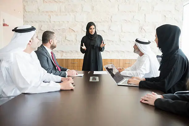 Photo of Arab businesswoman giving presentation to colleagues in office