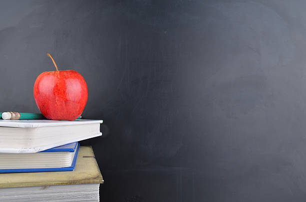istock Classroom concept with books an apple and blackboard with handwriting 470724822