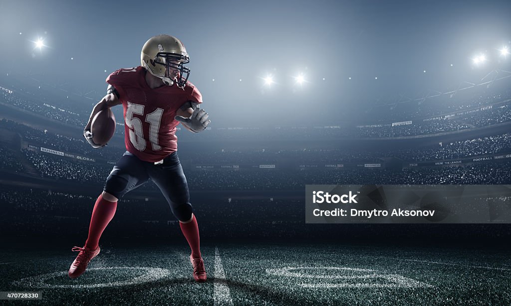 American football in action A male american football player makes a dramatic play. The stadium is blurred behind him.  The player is wearing generic unbranded american football uniform. The stadium is 3D rendered. American Football Player Stock Photo
