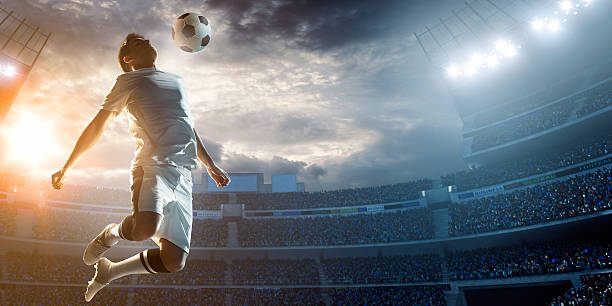 Soccer player kicking ball in stadium A male soccer player makes a dramatic play by jumping vertically. The stadium is blurred behind him. Only the lights of the stadium shine brightly, creating a halo effect around the bulbs. soccer soccer ball kicking adult stock pictures, royalty-free photos & images