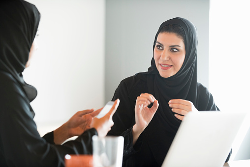Mujeres de negocio en ropa tradicional árabe en oficina discutiendo photo