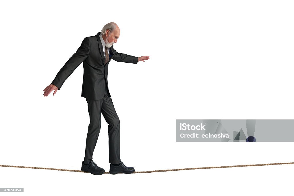 senior man walking a tightrope senior man walking a tightrope isolated on white Tightrope Stock Photo