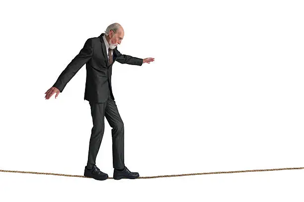 senior man walking a tightrope isolated on white