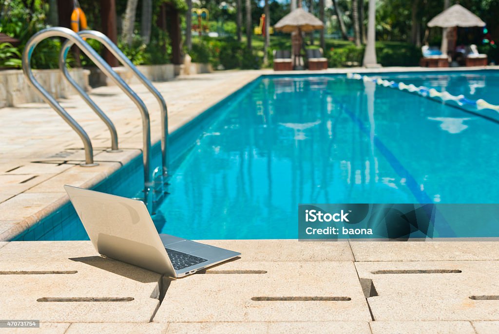 laptop beside a pool A laptop beside a swimming pool. 2015 Stock Photo