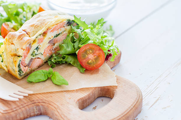 istock Strudel pie with salmon and spinach, served on wood board 470744636